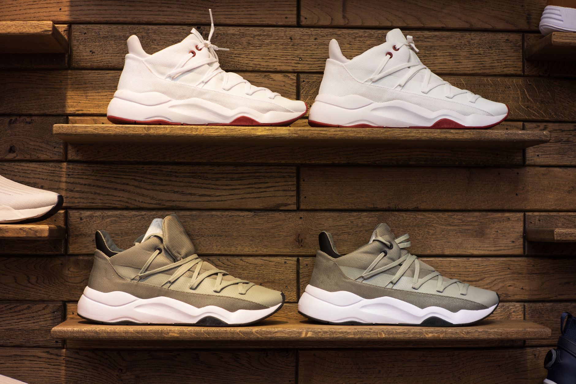 White and tan sneakers with red accents displayed on wooden shelves