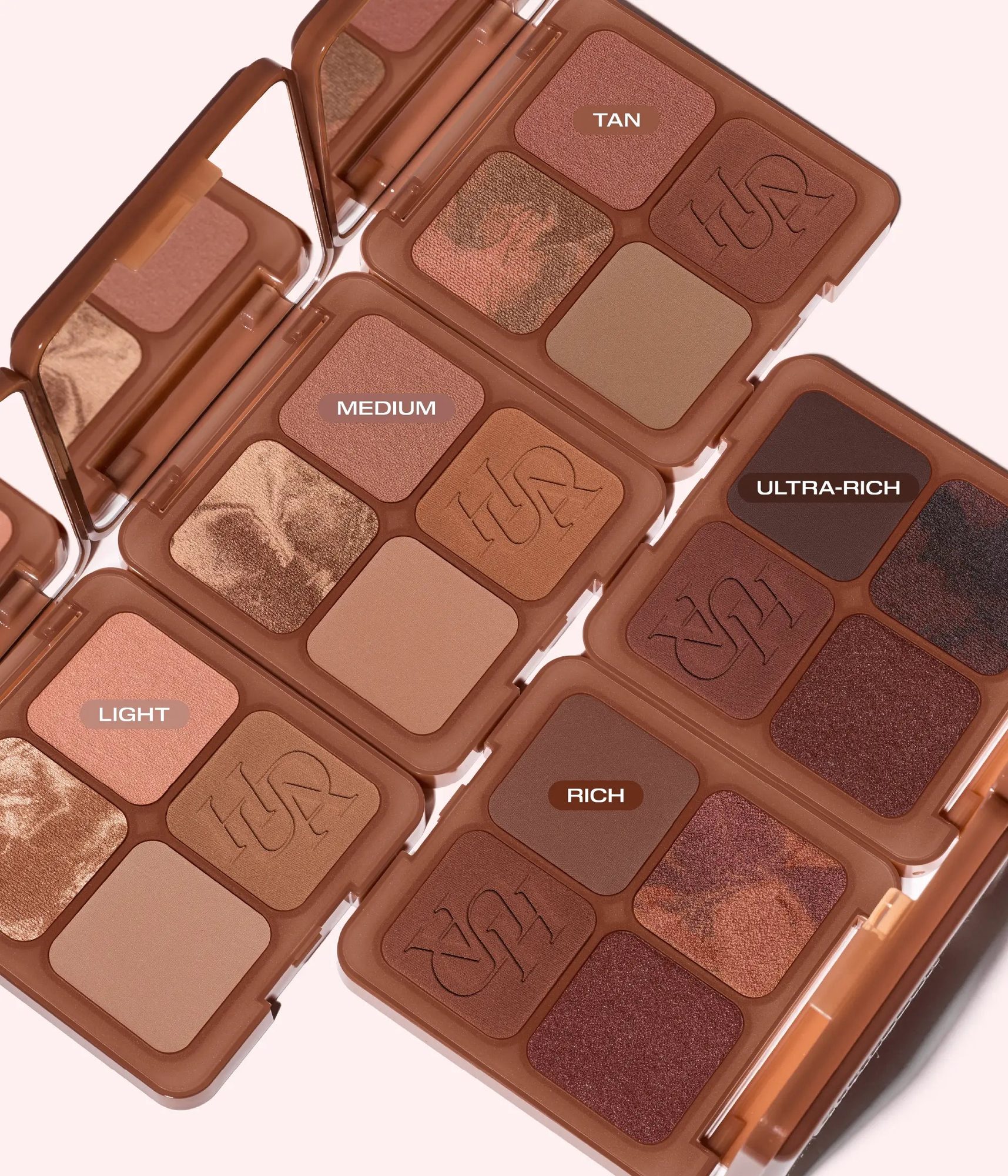 Multiple open eyeshadow palettes displaying shade varieties labeled Light, Medium, Rich, and Ultra-Rich