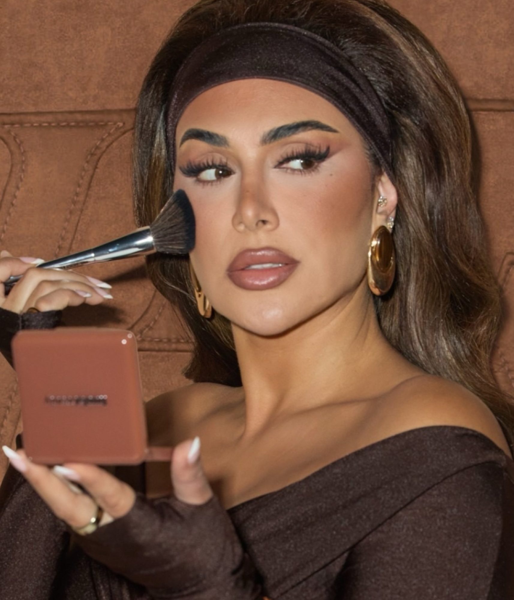Woman applying eyeshadow with brush while holding compact mirror