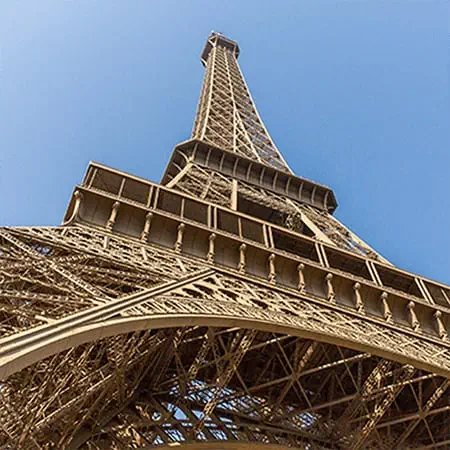 Upward view of iron lattice tower structure against blue sky