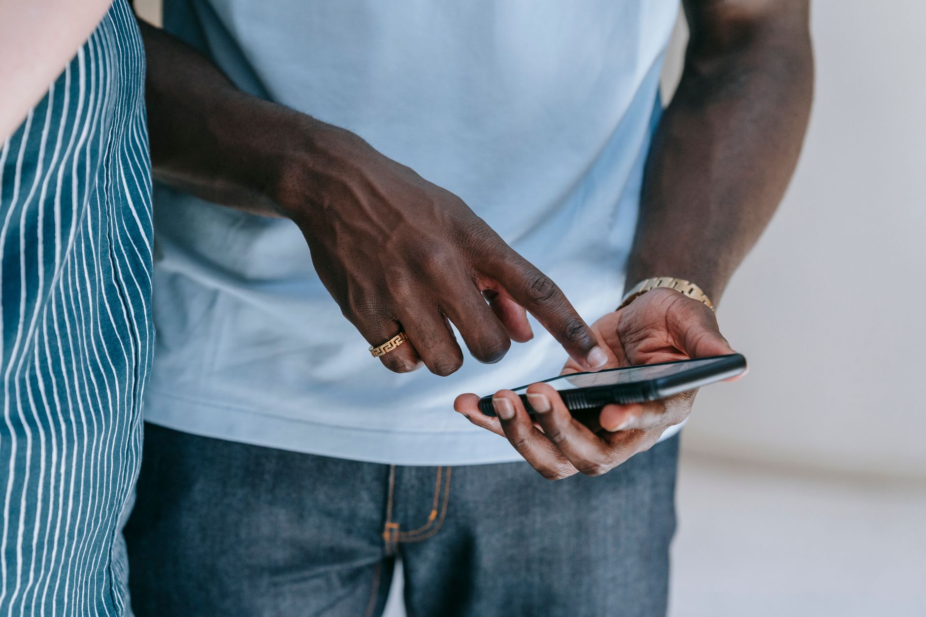 Man in light blue shirt and striped jacket holding and looking at a smartphone